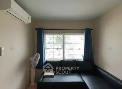 Cozy living room with air conditioning and stylish black sofa, perfect for relaxation.