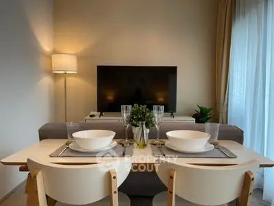 Elegant dining area seamlessly connects to a cozy living space, featuring modern furniture and tasteful decor, ideal for intimate gatherings.
