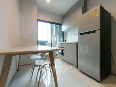 Modern kitchen with sleek appliances and dining area in stylish apartment.