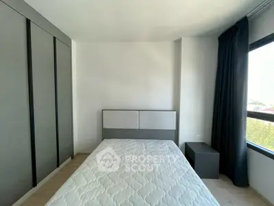 Modern bedroom with minimalist design and large window offering natural light.