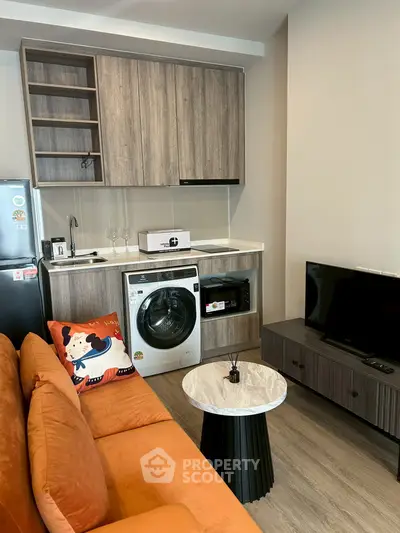 Modern living room with integrated kitchen featuring washing machine and stylish decor
