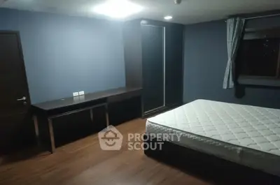 Spacious bedroom with modern furnishings and large window for natural light.