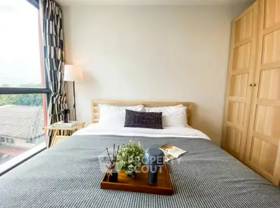Cozy bedroom with large window and stylish decor in modern apartment.