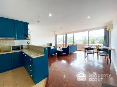 Spacious open-plan living room with modern kitchen and stunning city view balcony.