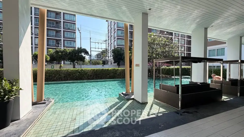 Luxurious poolside area with modern seating and lush greenery in a contemporary apartment complex.