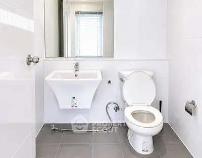 Modern bathroom with sleek fixtures and minimalist design, featuring a white sink and toilet.