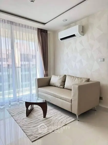 Modern living room with stylish sofa, glass coffee table, and large window for natural light.