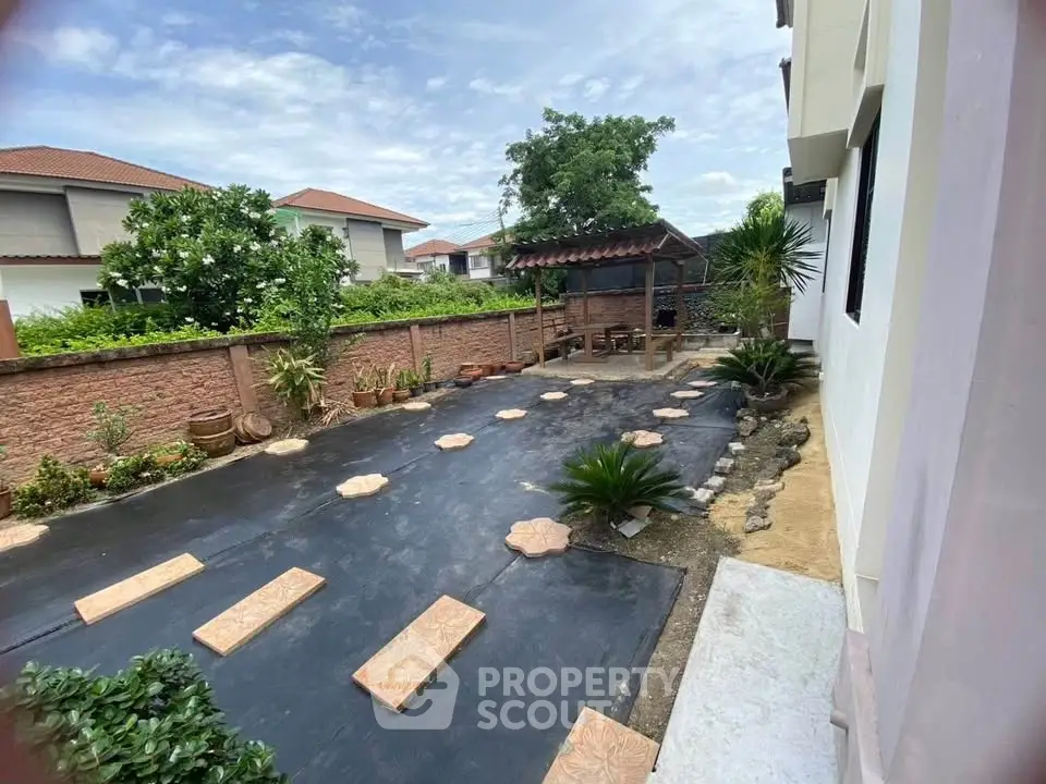 Spacious backyard with paved walkway and lush greenery in a suburban home.