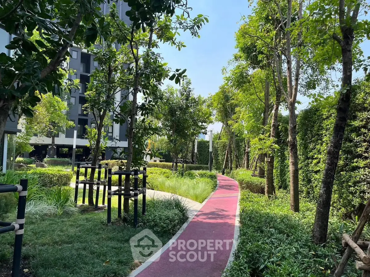 Lush garden pathway in modern residential complex with vibrant greenery and serene atmosphere.