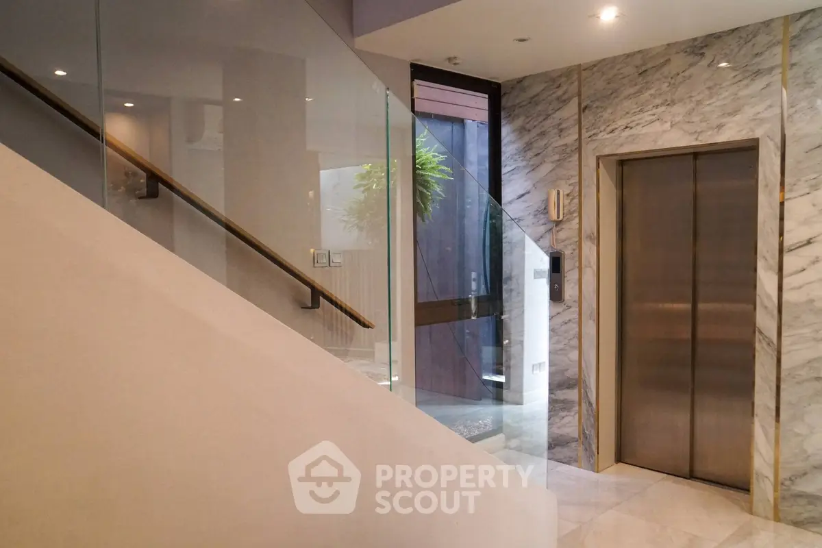 Luxurious marble-clad elevator lobby with modern design and glass accents.