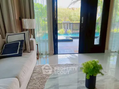 Luxurious living room with pool view, elegant decor, and natural light, perfect for relaxation and entertaining.