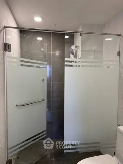 Modern bathroom with sleek glass shower enclosure and elegant tile design.