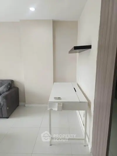 Modern minimalist interior with sleek white desk and cozy gray sofa in a bright room.