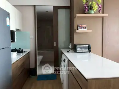 Modern kitchen with sleek countertops, washing machine, and compact oven in a stylish apartment.