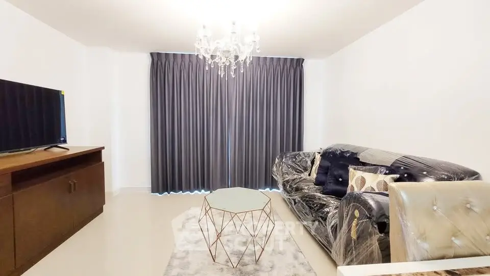 Modern living room with elegant chandelier and stylish furniture, perfect for cozy gatherings.