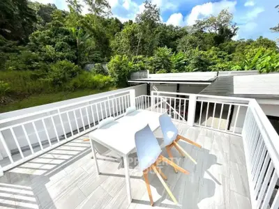 Spacious balcony with modern outdoor dining set and lush green views.