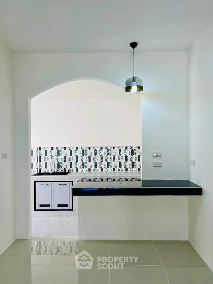 Modern kitchen with sleek black countertops and stylish backsplash in a bright, minimalist design.
