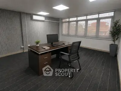 Modern office space with sleek desk, chair, and large windows offering natural light.