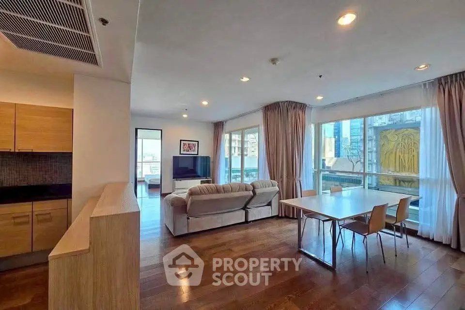 Spacious modern living room with large windows and wooden flooring in a stylish apartment.