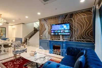 Luxurious living room with elegant decor, featuring a marble coffee table, plush blue sofa, and modern wall-mounted TV.