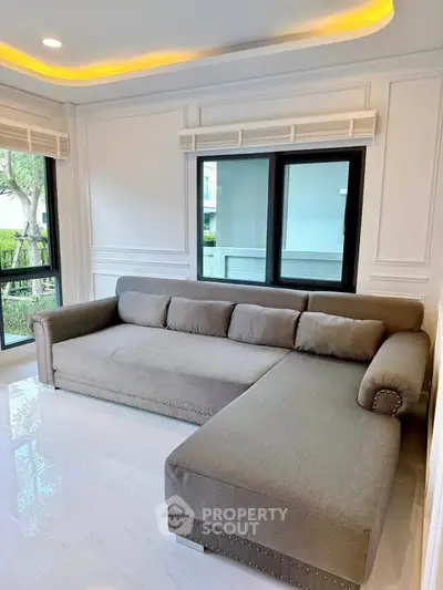 Spacious living room with modern L-shaped sofa and large windows offering natural light.