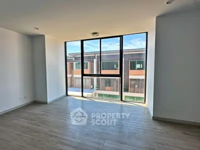 Spacious modern living room with large windows and wooden flooring, offering abundant natural light.