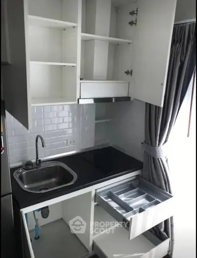 Modern kitchen with sleek cabinetry and stainless steel sink in a compact layout.