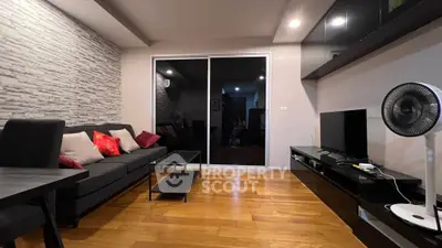 Modern living room with sleek furniture and wooden flooring, featuring a stylish entertainment unit and cozy seating area.