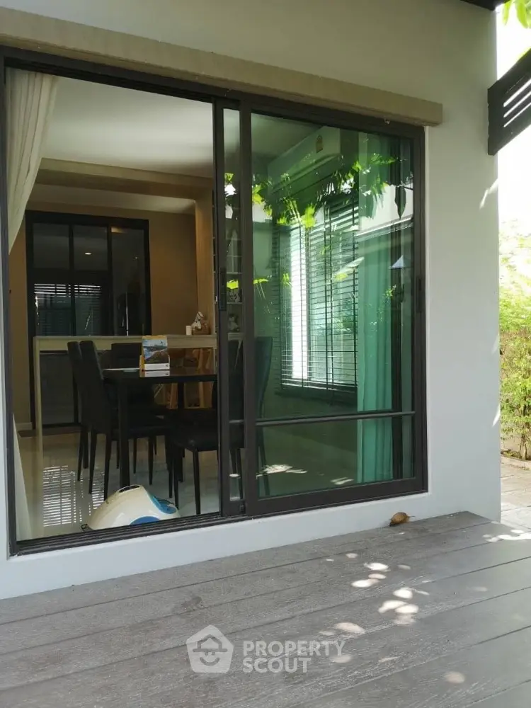 Modern home with sliding glass doors opening to a stylish dining area and lush greenery outside.