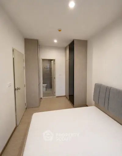 Modern minimalist bedroom with ensuite bathroom and sleek storage solutions.