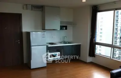 Modern compact kitchen with appliances in a high-rise apartment, featuring large windows and wooden flooring.