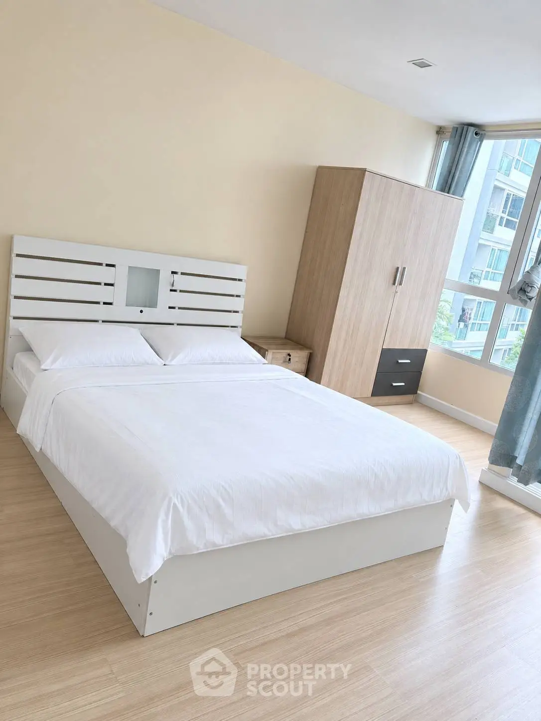 Spacious bedroom with modern furniture and large window offering natural light.