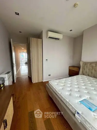 Spacious bedroom with wooden flooring and modern air conditioning unit.