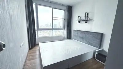 Modern bedroom with large window offering stunning city views, minimalist design and ample natural light.