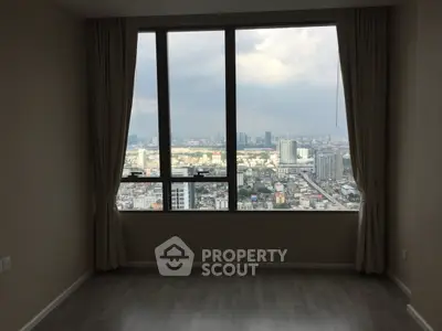 Spacious room with large windows offering a stunning city view, perfect for urban living.