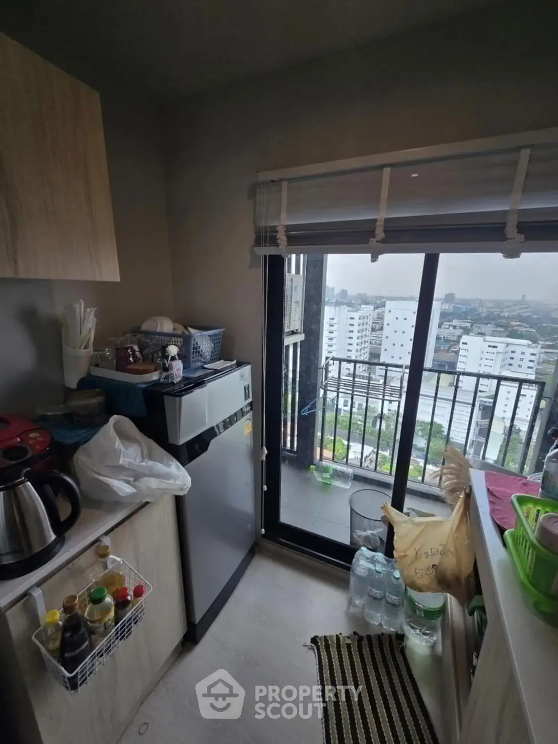Cozy kitchen with balcony offering city view, compact appliances, and modern decor.