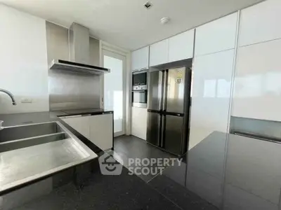 Modern kitchen with sleek cabinetry, stainless steel appliances, and black countertops.