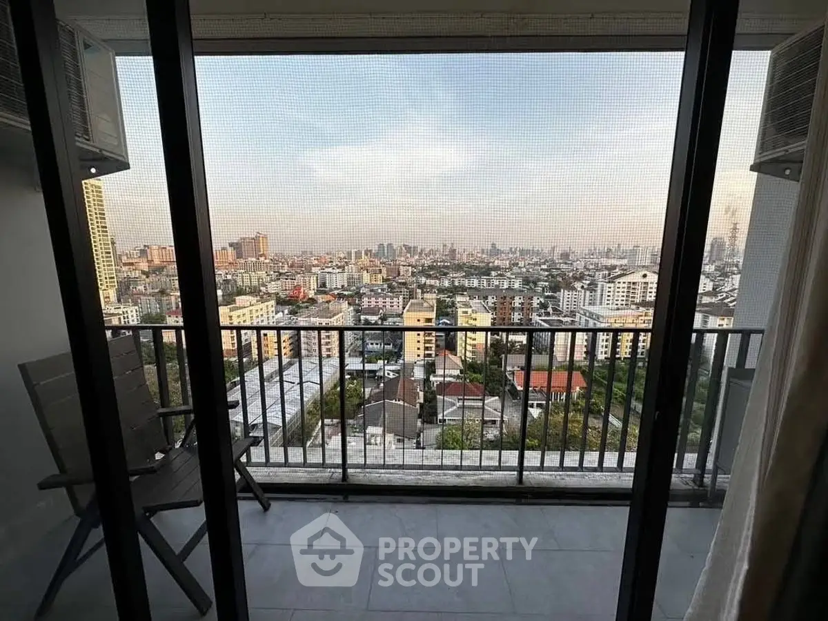 Stunning cityscape view from high-rise balcony with seating area.