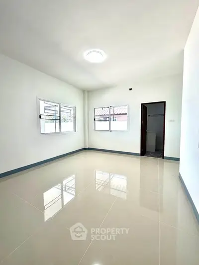 Spacious empty room with glossy tiled floor and large windows, perfect for customization.