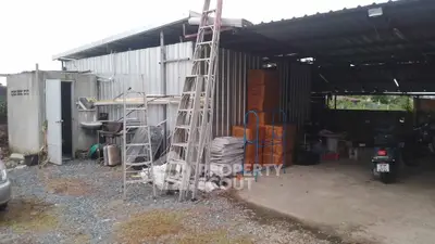 Industrial storage area with metal shed, ladders, and stacked boxes, ideal for warehouse or workshop use.