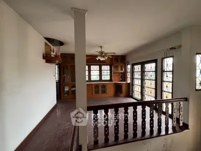 Spacious living room with wooden cabinets and large windows offering natural light