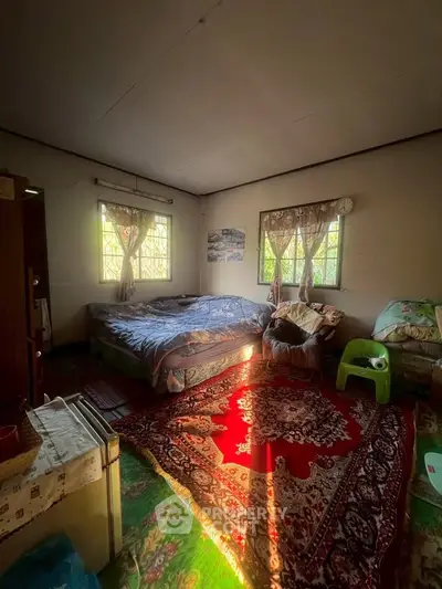 Cozy bedroom with natural light, colorful rugs, and comfortable furnishings.