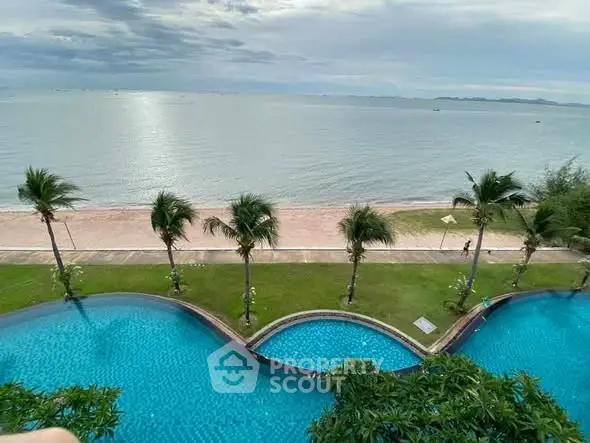 Stunning beachfront view with luxurious pool and palm trees, perfect for relaxation and leisure.