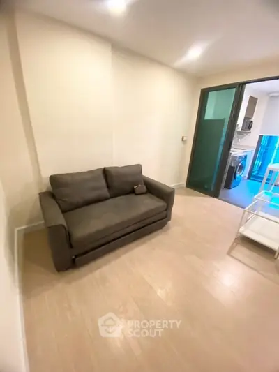 Modern living room with cozy sofa and view into sleek kitchen area