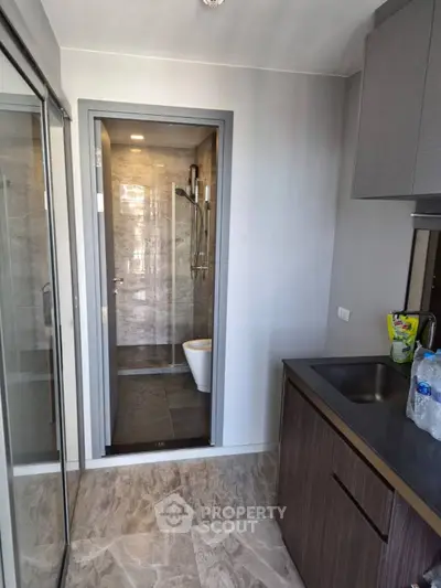 Modern compact bathroom with sleek design and adjacent kitchen area