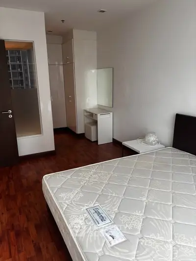 Spacious bedroom with wooden flooring and modern furniture in a high-rise apartment.