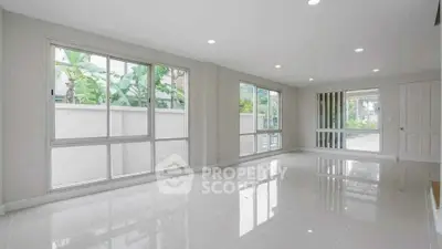 Spacious modern living room with large windows and glossy tile flooring.