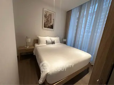Cozy bedroom with modern decor and large window, perfect for relaxation and comfort.