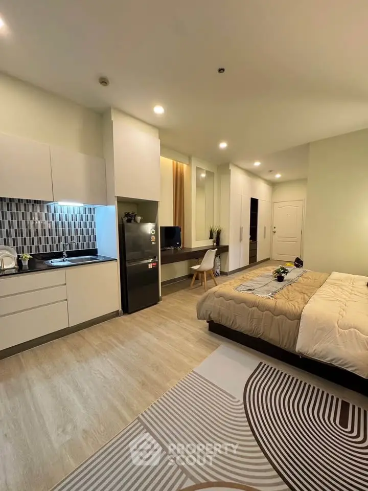 Modern studio apartment with open kitchen and cozy sleeping area, featuring stylish decor and ample lighting.