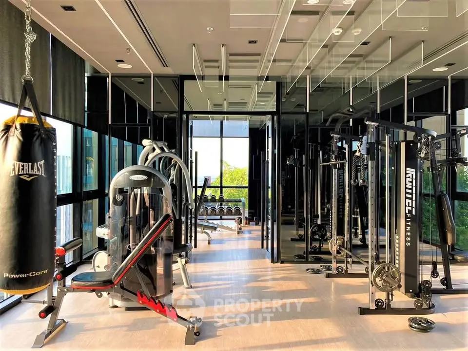 Luxurious gym with modern fitness equipment and large windows offering natural light.
